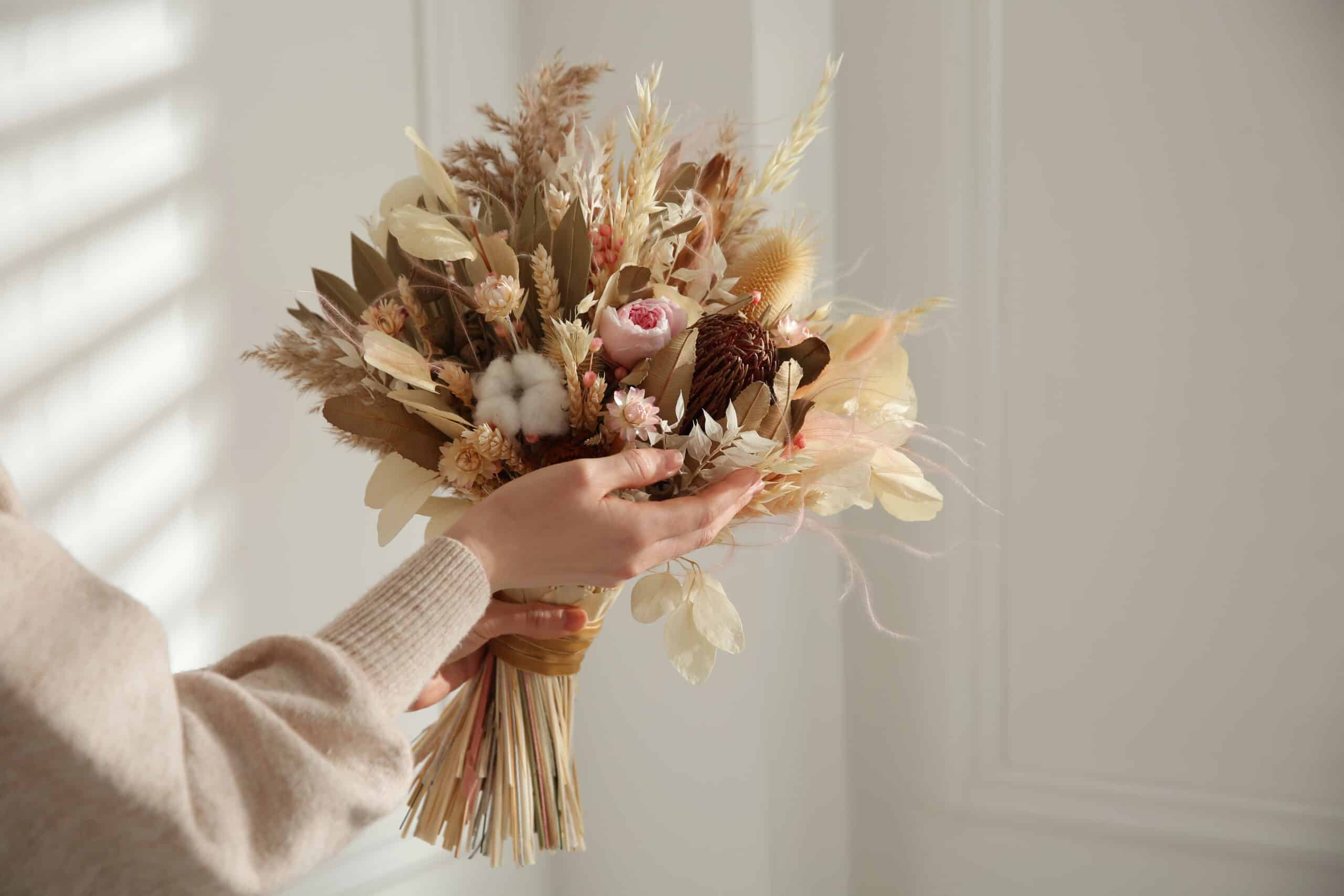 Woman holding beautiful dried flower bouquet at home, closeup